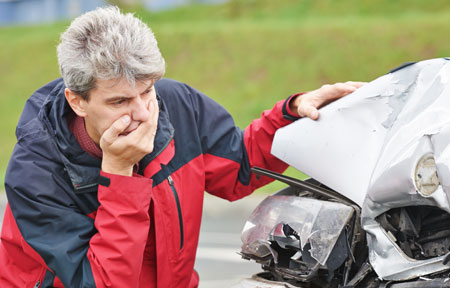 Man inspecting his car after an accident