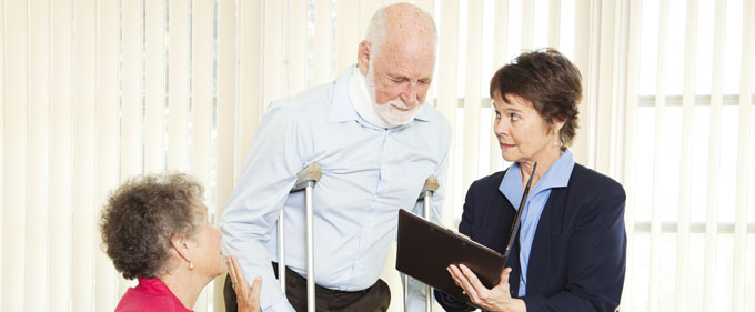 Man on crutches looks at paperwork with female lawyer and additional woman present