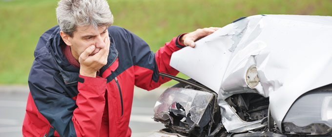 Man inspecting his car after an accident